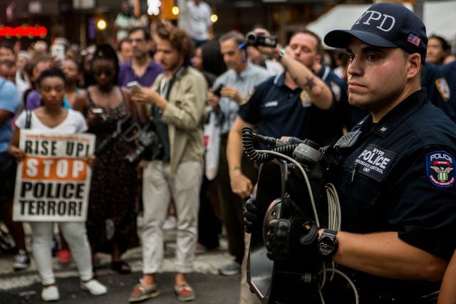 An NYPD officer wields a controversial LRAD sound cannon at last night's protest.